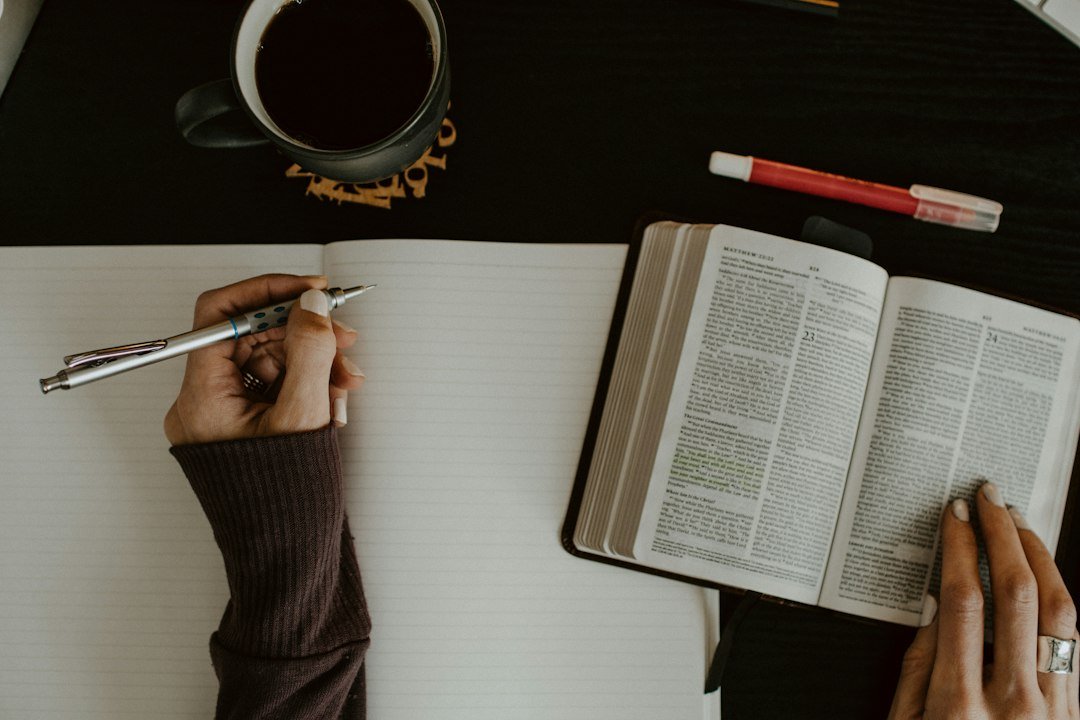 Mãos próximas de uma Bíblia aberta e de um caderno